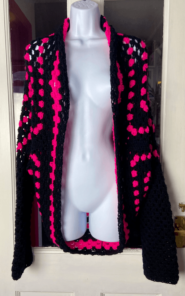 Pink and black shrug style cardigan.